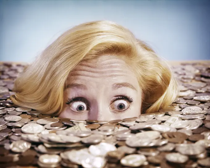 1960s PANICKED BUG-EYED BLOND YOUNG WOMAN BURIED UP TO HER NOSE IN PILE OF COINS AND CURRENCY