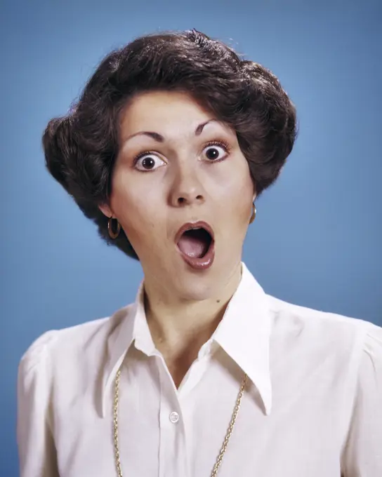 1970s PORTRAIT BRUNETTE WOMAN WITH SURPRISED SHOCKED ALARMED FACIAL EXPRESSION MOUTH AND EYES WIDE OPEN LOOKING AT CAMERA