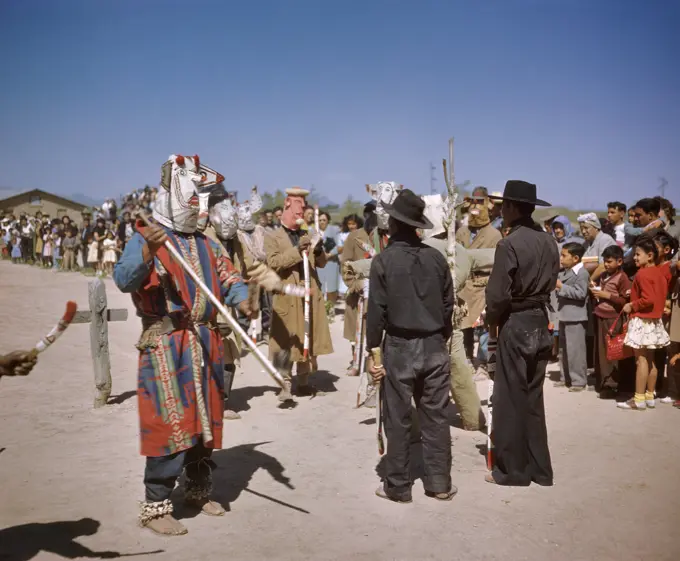 1950s CROWD OF PEOPLE WATCHING NATIVE AMERICAN YAQUI INDIAN MEN IN MASKS PERFORM TRIBAL CEREMONY RITUAL TUCSON AZ USA