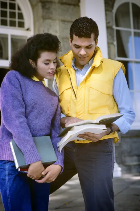 1980s AFRICAN AMERICAN COLLEGE COUPLE LOOKING AT TEXTBOOK