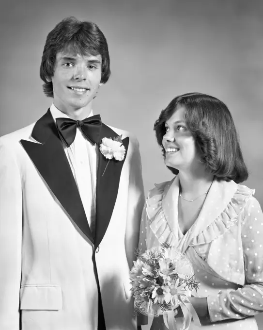 1970s TEEN COUPLE DRESSED UP FOR PROM DANCE FORMAL ATTIRE GIRL HOLDING BOUQUET LOOKING UP AT TALL BOY