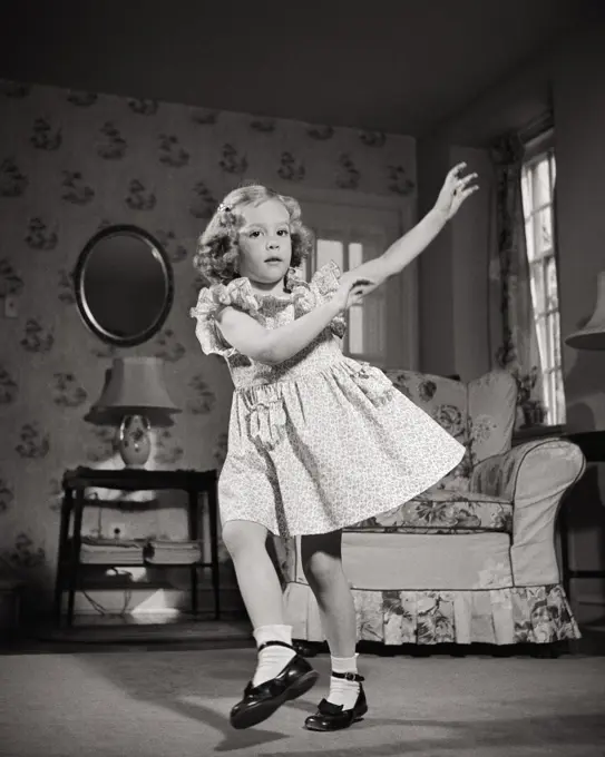 1940s BLOND GIRLIN DRESS WEARING MARY JANE SHOES LOOKING AT CAMERA DANCING HOKEY-POKEY IN LIVING ROOM