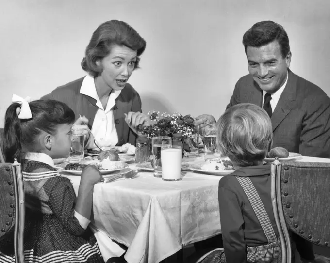 1960s FAMILY OF FOUR EATING DINNER TOGETHER