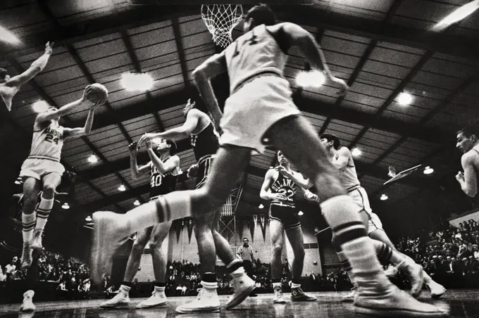 1960s 1970s COLLEGIATE BASKETBALL GAME PLAYERS UNDER THE HOOP SHOOTING TO SCORE EXTREME LOW ANGLE BACK VIEW