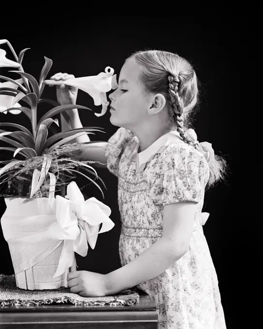 1940s GIRL WITH BRAIDS SNIFFING SMELLING SCENT OF A POTTED EASTER LILY