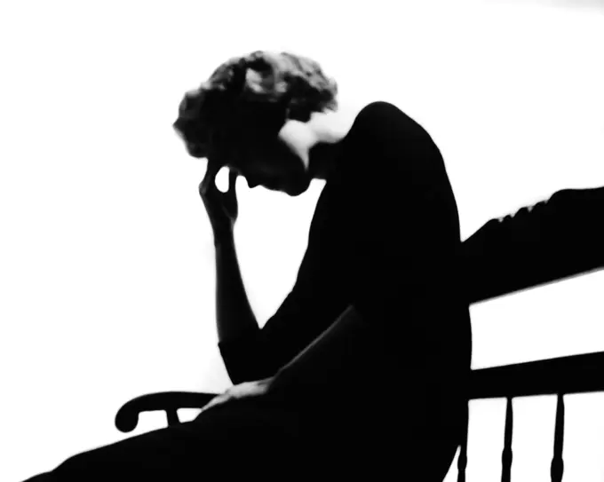 1950s ANONYMOUS SILHOUETTED SUFFERING AILING ILL PSYCHOLOGICALLY DISTURBED WOMAN SITTING ON BENCH PRESSING FINGERS TO FOREHEAD