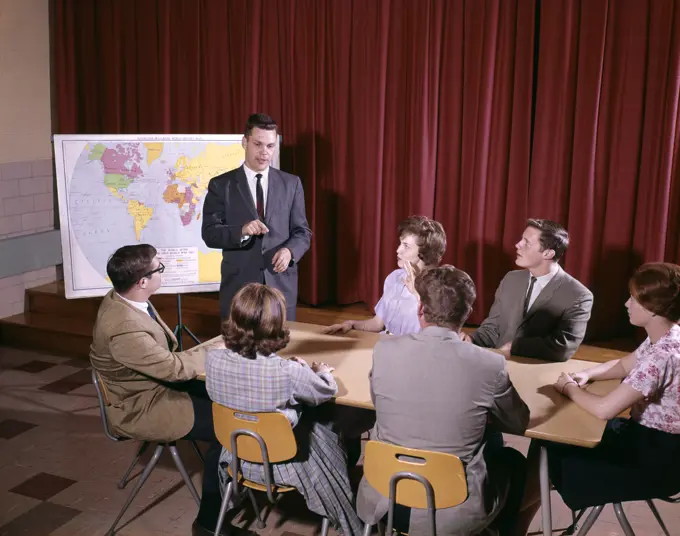 1960S Group Of Students Around Table Teacher Standing By Map