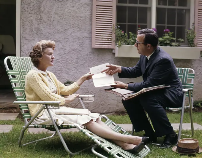 1960S Man Showing Material In Papers To Woman Sitting Outside Suburban House Insurance Medical Salesman