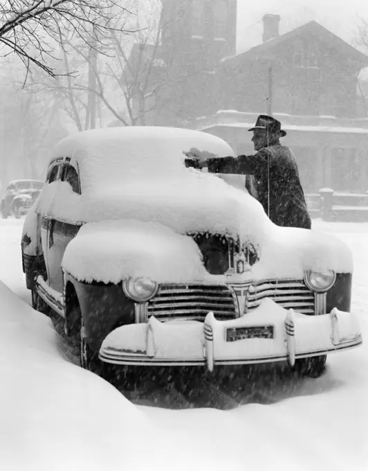 1940S Man Removing Snow From Windshield Of Parked Car Covered In Blizzard Outdoor