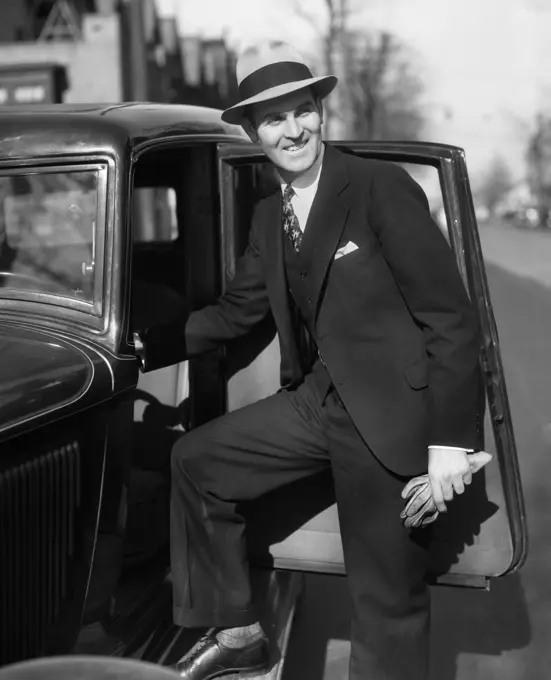 1930S Smiling Man In Suit And Hat Holding Gloves Stepping Into Automobile Driver Seat