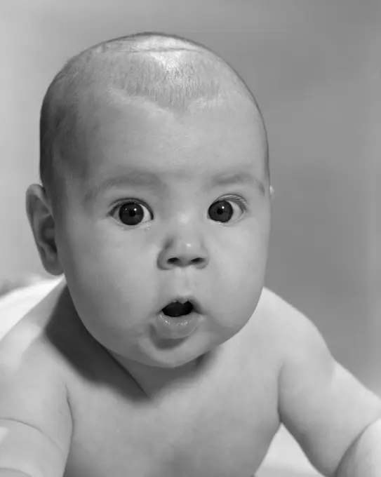 1960S Close-Up Of Baby Lying On Stomach Wide-Eyed With Mouth Open