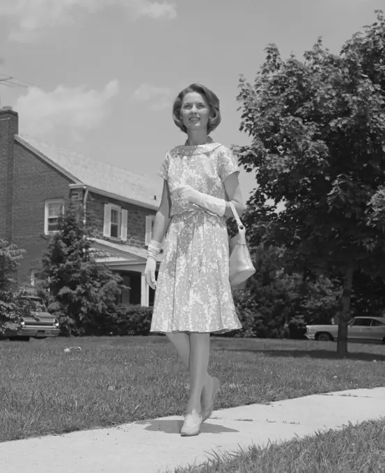 1960S Woman Wearing Print Dress Holding Handbag Walking Down Suburban Street