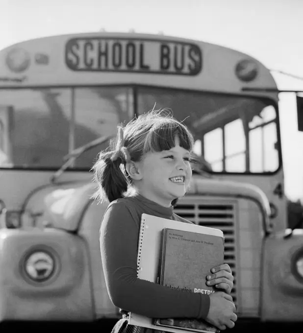 1980S Girl Holding Books Standing In Front Of School Bus