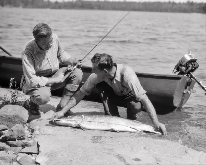 1930S TWO MEN FISHERMAN AND GUIDE MEASURE LARGE FISH LAKE OF THE WOODS ONTARIO CANADA