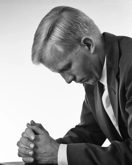 1960s RELIGIOUS BLOND MAN WEARING COAT AND TIE KNEELING HEAD BOWED HANDS CLASPED IN PRAYER