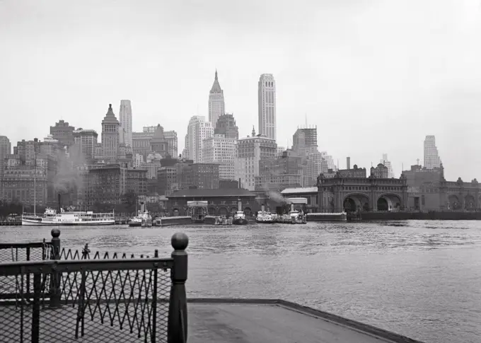 1930s SKYLINE OF LOWER MANHATTAN BUSINESS DISTRICT SIGHT SEEING BOATS TERMINAL SLIPS FROM DECK OF STATEN ISLAND FERRY NYC USA 