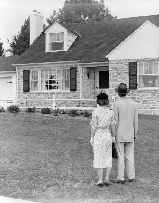 1940S 1950S Couple Standing Outside Looking At Stone Suburban House
