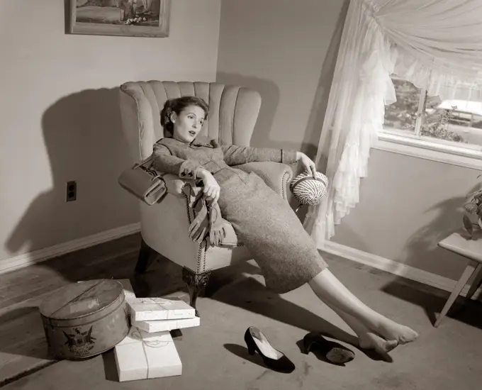 1950S Exhausted Female Slumped In Chair With Shoes Off After Shopping