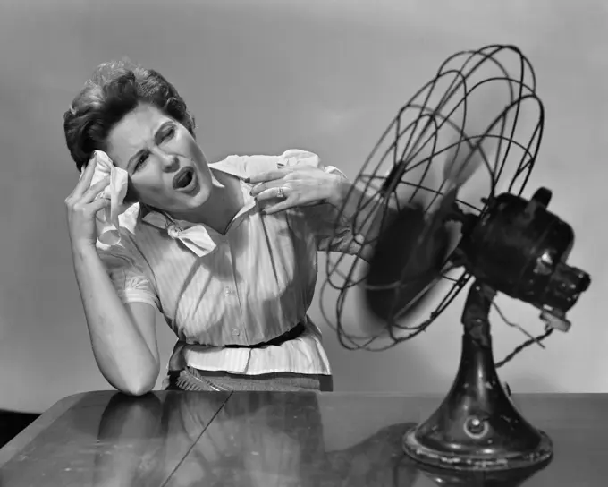 1950S Woman Sitting In Front Of Fan Wiping Forehead Very Hot