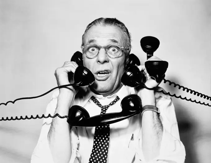 1950S 1960S Portrait Of Frazzled Businessman Trying To Answer Four Black Telephones Phones At Once