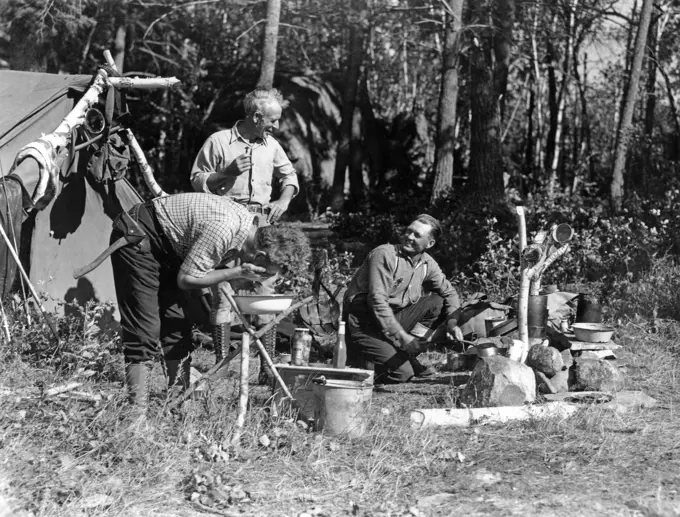 1940S Men At Campsite One Washing His Face At Tripod Stand The Other Tending Campfire Canada Lake Of The Woods Ontario