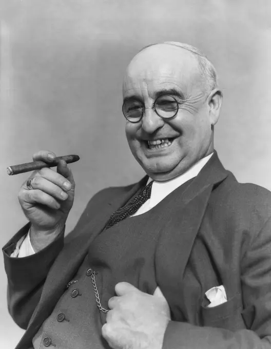 1930S Elderly Businessman In 3-Piece Suit & Glasses Leaning Back Smiling With Cigar In Hand