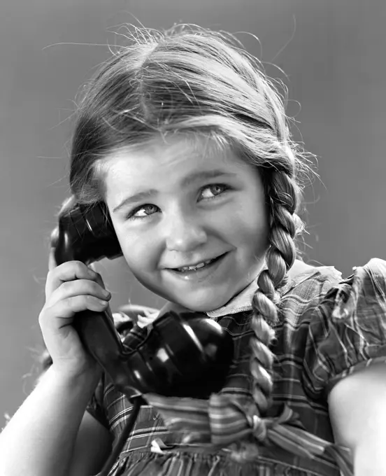 1930S 1940S Portrait Of Smiling Little Girl With Long Pigtails Talking On Telephone