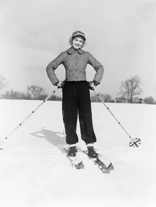 1940S 1950S Smiling Woman On Skis With Cap And Quilted Ski Jacket With Both Hands On Hips