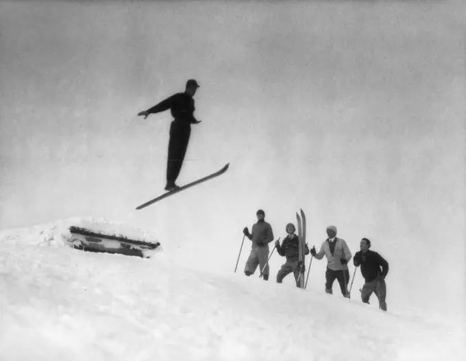 1920S Men In Snow Wearing Wooden Skis Watching Ski Jumper Using One Single Ski