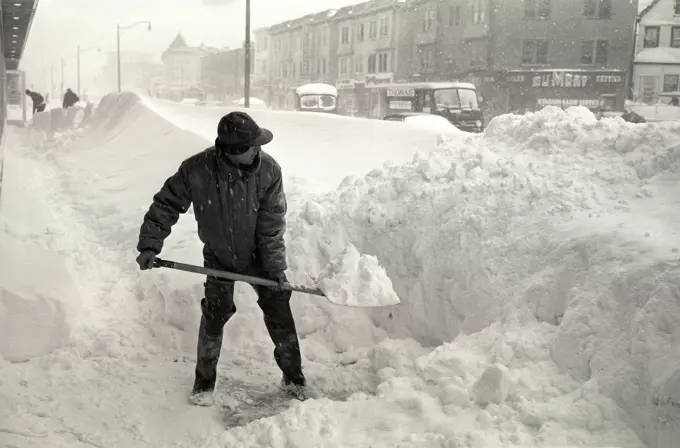 1940S Bundled Up Man With Snow Shovel Shoveling City Side Walk During Winter Storm