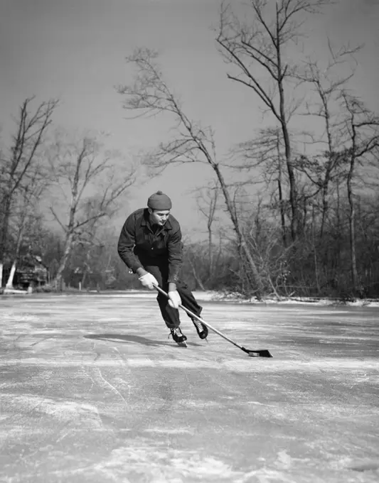 1940S Man Playing Ice Hockey On Frozen Lake Controlling Puck With Stick