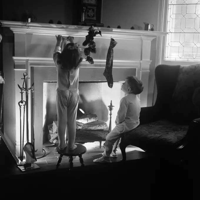 1940S Boy Girl Hanging Christmas Stockings At Fireplace