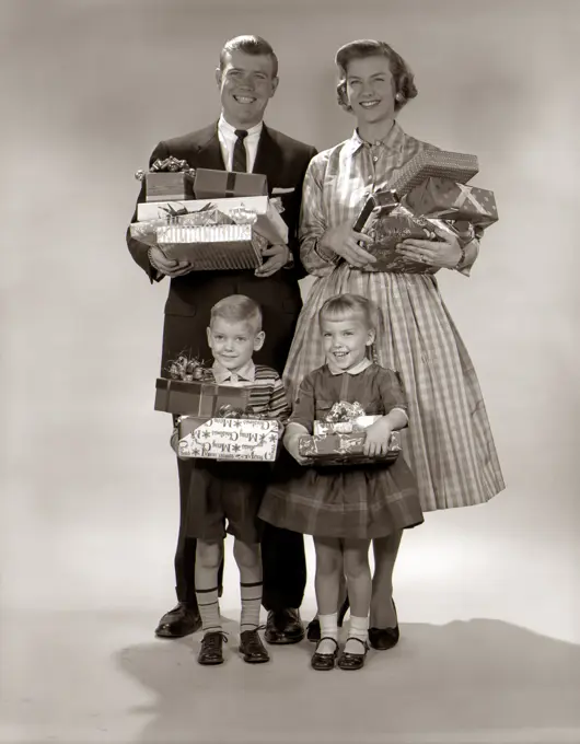 1960S Family Portrait Of Four Mother Father Boy Girl Carrying Christmas Gifts Wrapped Presents