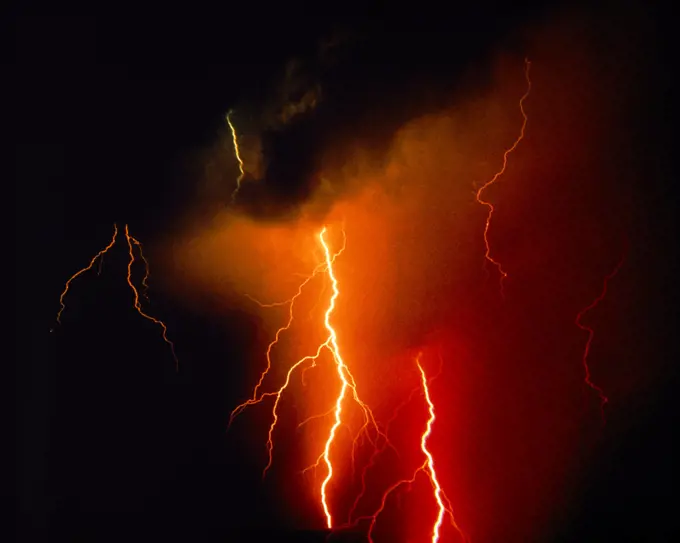 1980s RED AND YELLOW POWERFUL LIGHTNING BOLTS STRIKING FROM DARK CLOUDS AT NIGHT