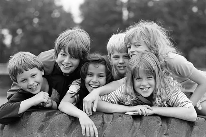 1970S, 1980S Group Of Six Boys & Girls Gathered Together On Large Playground Tire