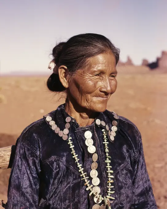 1950s 1960s PORTRAIT MATURE SENIOR NAVAJO WOMAN WEARING TURQUOISE NECKLACE VELVET BLOUSE ADORNED WITH DIMES & QUARTERS 