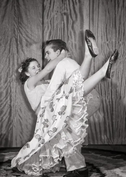 1950s LAUGHING ACTIVE TEEN COUPLE DOING JITTERBUG DANCE LIFT MOVE PETTICOATS SHOWING