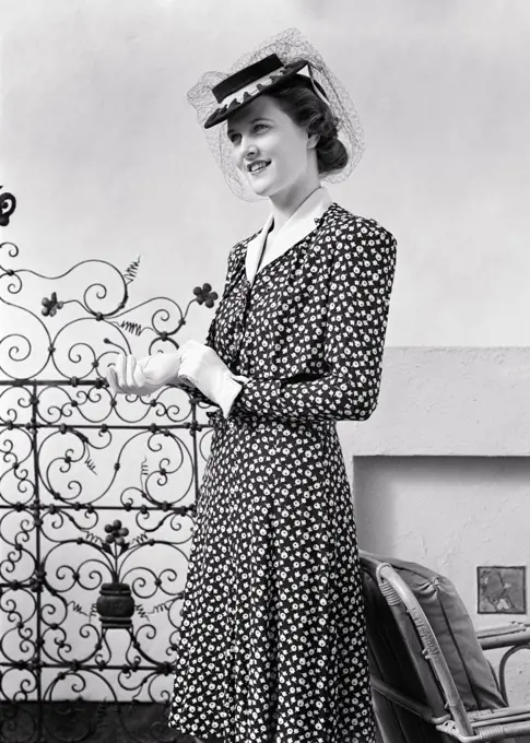 1940s FASHIONABLE TALL SLENDER BRUNETTE WOMAN WEARING PRINT DRESS WITH WHITE COLLAR GLOVES AND PERKY HAT WITH ATTACHED NET VEIL