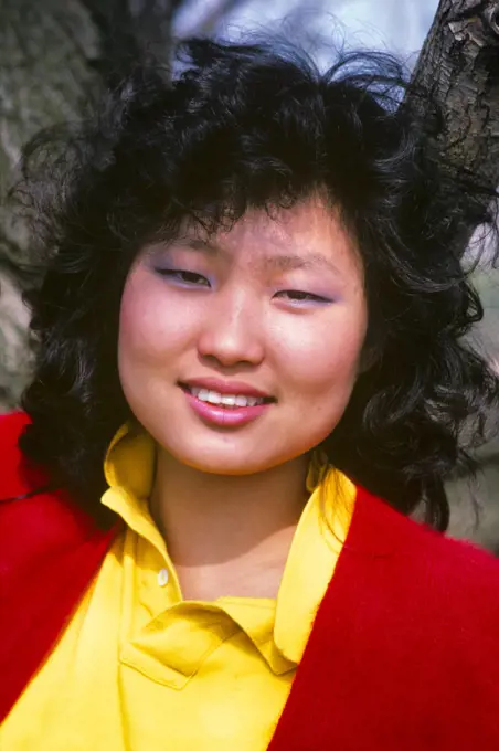 1980s PORTRAIT SMILING YOUNG KOREAN WOMAN WEARING YELLOW BLOUSE RED SWEATER LOOKING AT CAMERA