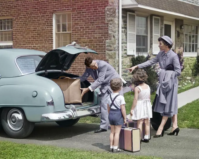 1950s FAMILY PUTTING LUGGAGE SUITCASES INTO TRUNK OF CAR