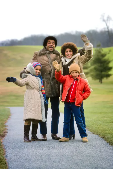 1970s 1980s PORTRAIT AFRICAN-AMERICAN FAMILY MOTHER FATHER TWO KIDS OUTDOORS WEARING HATS COATS GLOVES LOOKING WAVING AT CAMERA