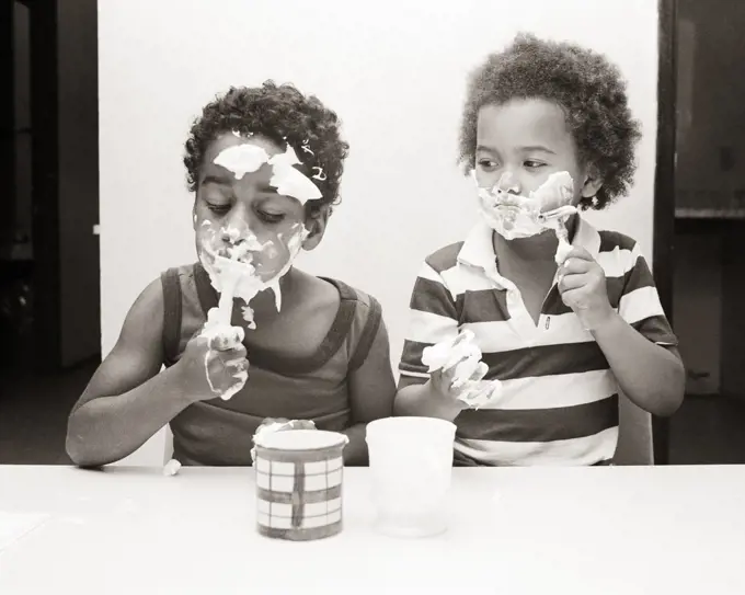 1980s TWO YOUNG AFRICAN-AMERICAN BOYS BROTHERS PLAYING AT SHAVING WITH SHAVING CREAM SOAP AND BLADELESS SAFETY RAZORS