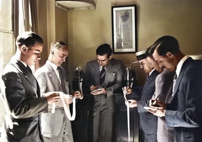 1920s 1930s SIX MEN INVESTORS AND STOCK BROKERS READING PAPER TICKER TAPE INVENTED IN 1867 BY EDWARD CALAHAN NEW YORK CITY USA