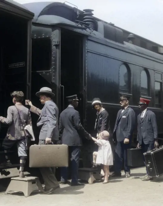 1920s 1930s FAMILY MOTHER FATHER SON DAUGHTER BOARDING PASSENGER TRAIN ASSISTED BY TRAINMAN AND PORTERS CARRYING LUGGAGE OUTDOOR