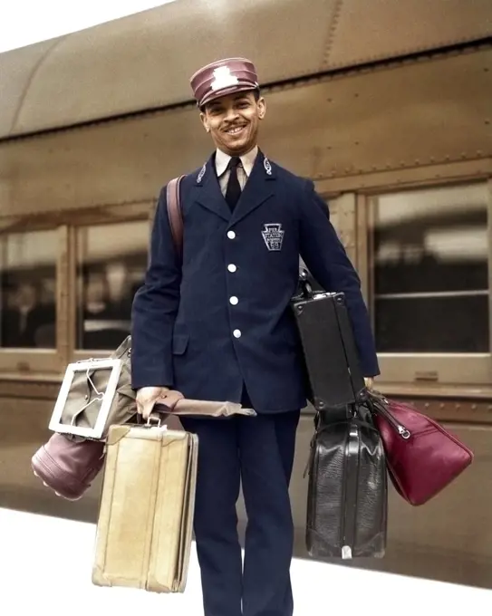 1930s 1940s PORTRAIT SMILING AFRICAN AMERICAN MAN PASSENGER RAILROAD TRAIN RED CAP PORTER LOOKING AT CAMERA CARRYING LUGGAGE