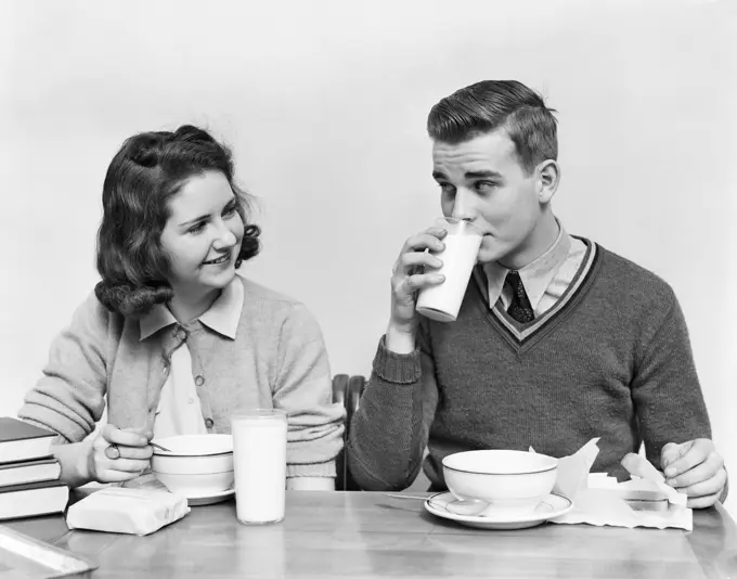 1940s TEENAGE GIRL AND BOY EATING SCHOOL    LUNCH SOUP SANDWICHES TOGETHER BOY DRINKING MILK