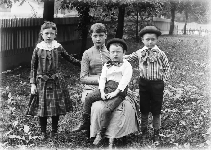 1890s 1900s FAMILY GROUP PORTRAIT SIBLINGS GIRL SISTER TWO BOYS BROTHERS OUTSIDE IN BACKYARD WITH MOTHER LOOKING AT CAMERA