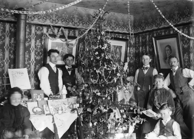 1890 1890s TURN OF CENTURY GROUP PORTRAIT FAMILY THREE GENERATIONS POSING BY CHRISTMAS TREE GIFTS ON TABLE