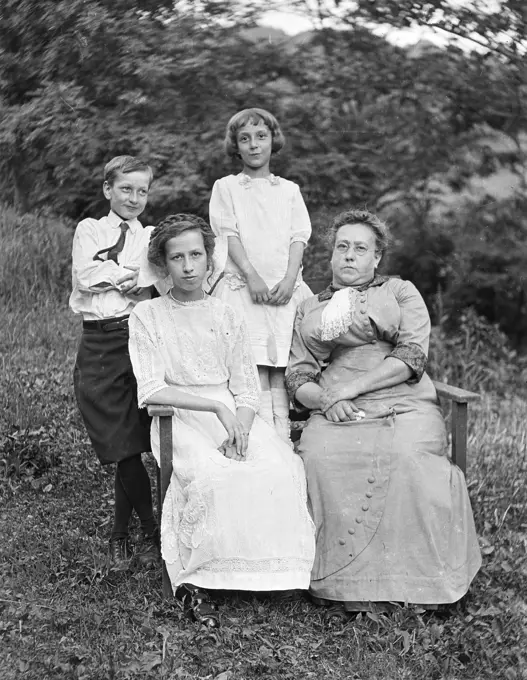 1800s 19TH CENTURY MOTHER AND THREE CHILDREN  SITTING AND STANDING TOGETHER OUTDOORS LOOKING AT CAMERA