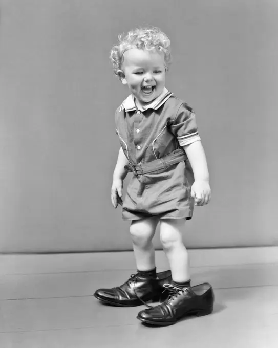 1930s 1940s LAUGHUNG CURLY BLOND HEADED BABY BOY WALKING IN FATHER'S ADULT SHOES FOLLOWING FOOTSTEPS 